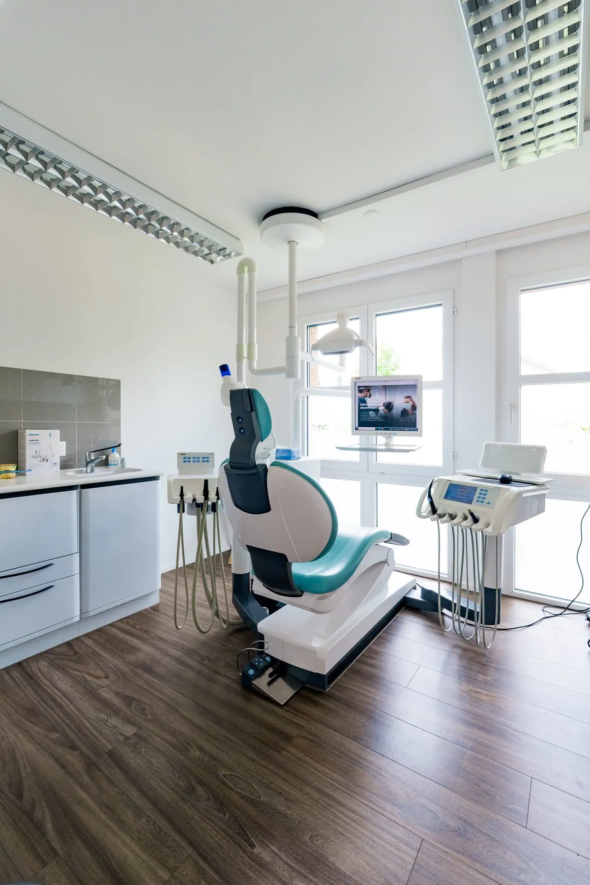 Behandlungszimmer in Küsnacht mit Behandlungsstuhl und Bildschirm am Fenster